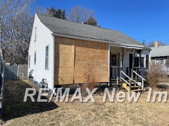 view of front of home with roof with shingles and fence