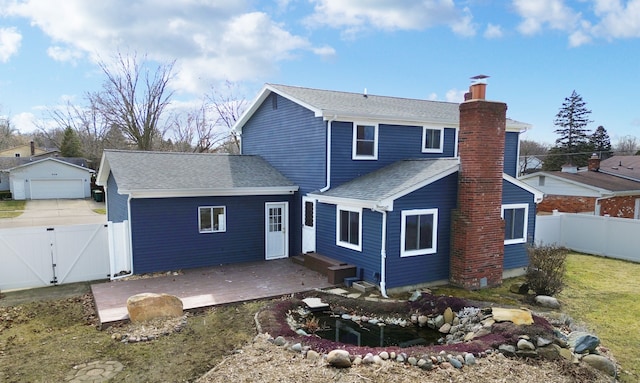 rear view of property featuring a gate, fence, roof with shingles, a chimney, and a deck