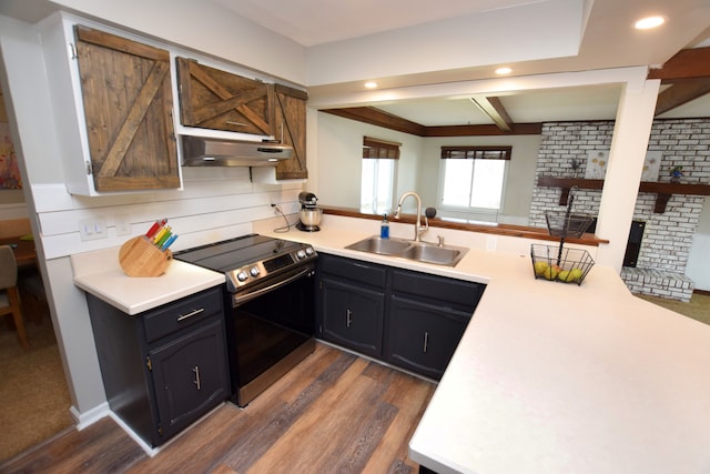 kitchen with under cabinet range hood, stainless steel electric range, light countertops, and a sink