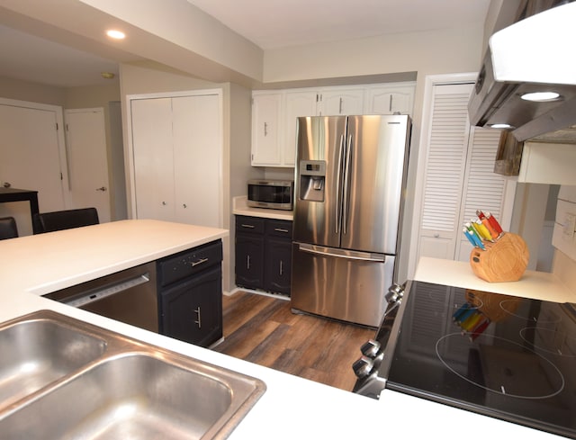 kitchen featuring a sink, stainless steel appliances, white cabinets, extractor fan, and dark wood-style flooring