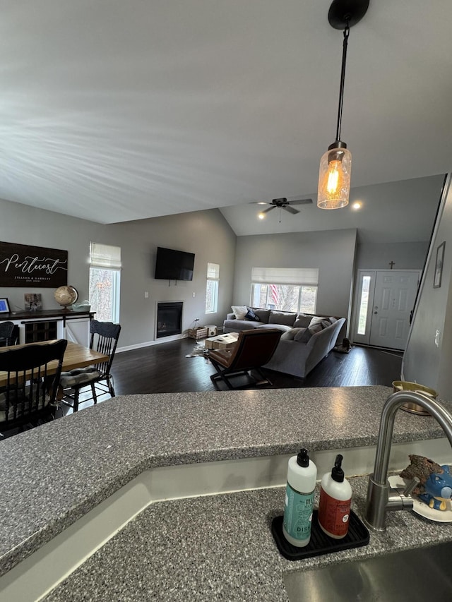 kitchen with vaulted ceiling, wood finished floors, a fireplace, and open floor plan