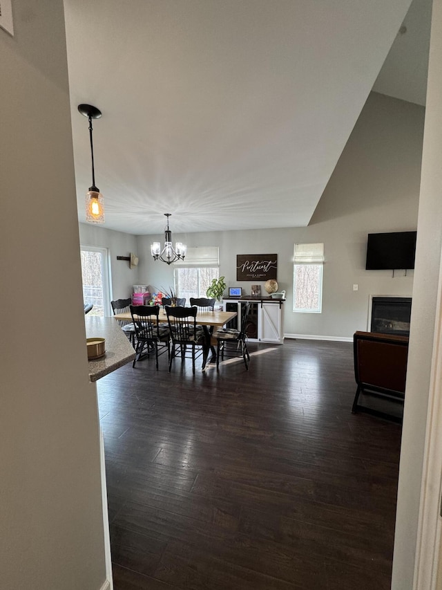 dining area featuring a wealth of natural light, baseboards, an inviting chandelier, and dark wood-style floors