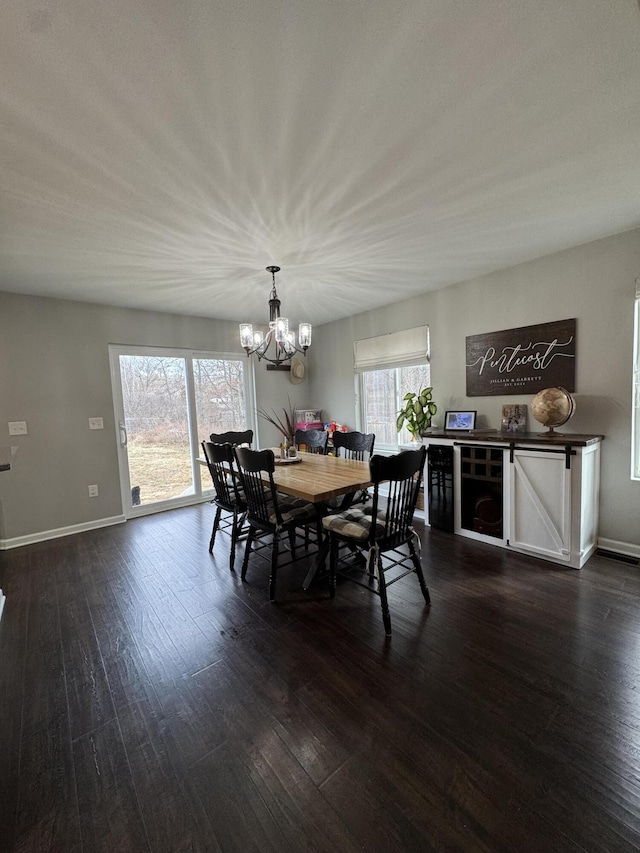 dining area with a wealth of natural light, an inviting chandelier, and dark wood-style flooring