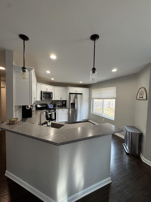 kitchen with a peninsula, dark wood-style floors, white cabinets, stainless steel appliances, and a sink