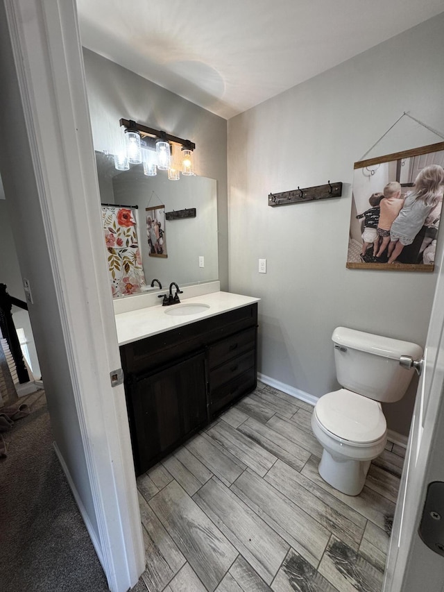 bathroom with vanity, toilet, baseboards, and wood tiled floor