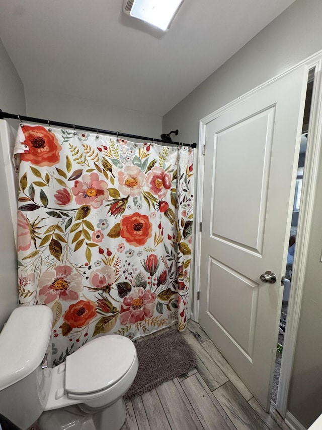 bathroom featuring toilet, a shower with curtain, and wood finished floors