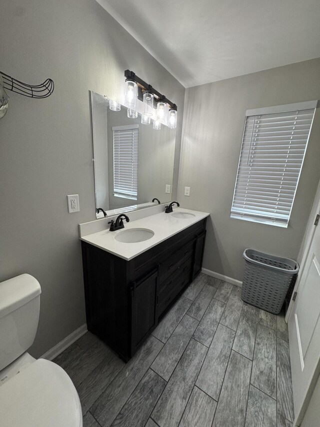 full bathroom with baseboards, toilet, wood finish floors, and a sink