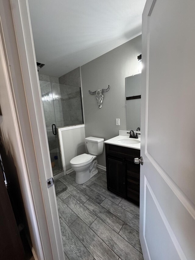 bathroom featuring vanity, baseboards, wood finish floors, a shower stall, and toilet