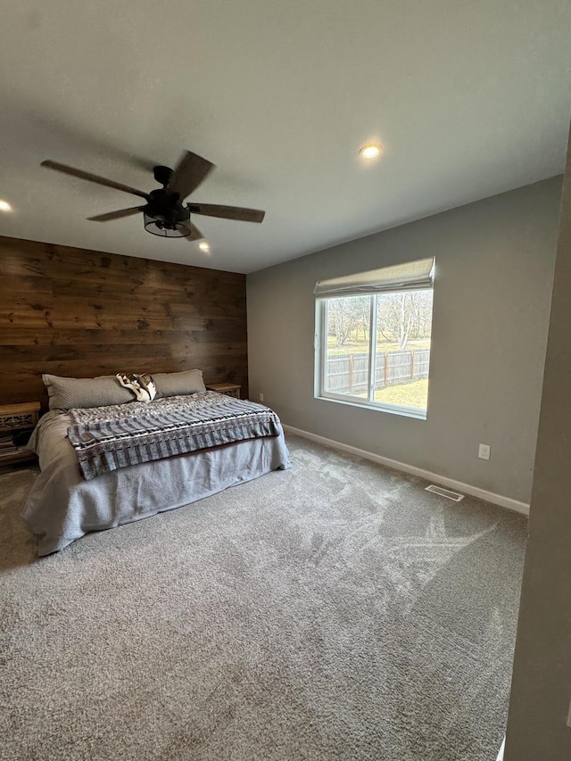 unfurnished bedroom with baseboards, visible vents, carpet floors, recessed lighting, and wood walls