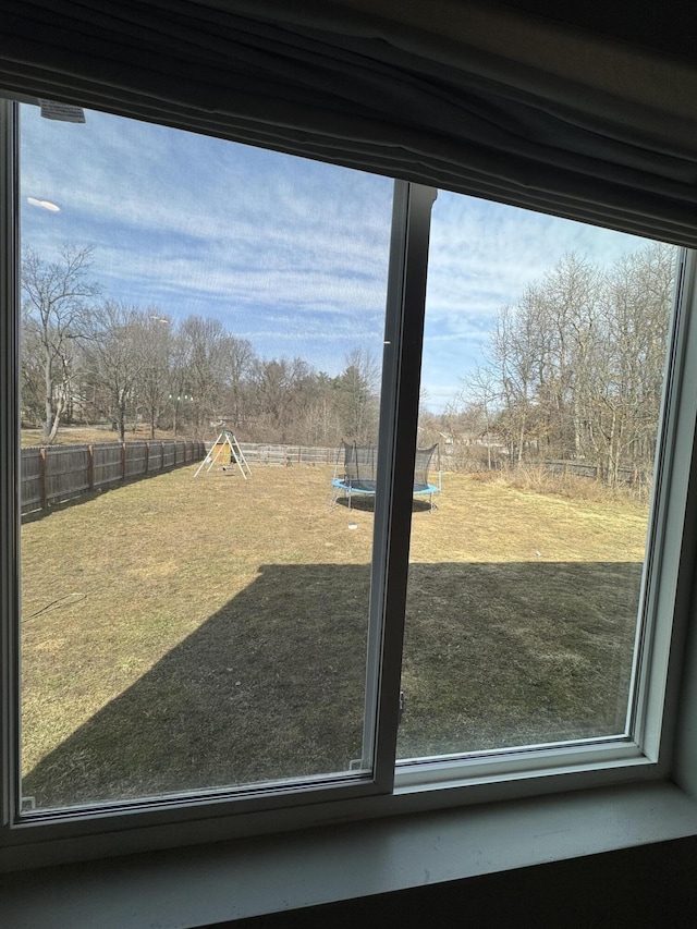 view of yard featuring a trampoline, a fenced backyard, and a playground