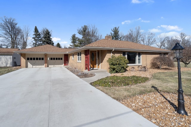 ranch-style house featuring driveway, roof with shingles, an attached garage, brick siding, and a chimney