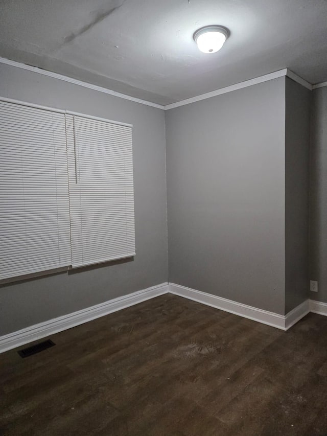 spare room featuring visible vents, baseboards, dark wood-type flooring, and ornamental molding