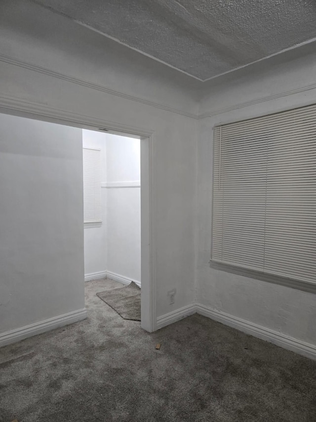 carpeted empty room with a textured ceiling and baseboards