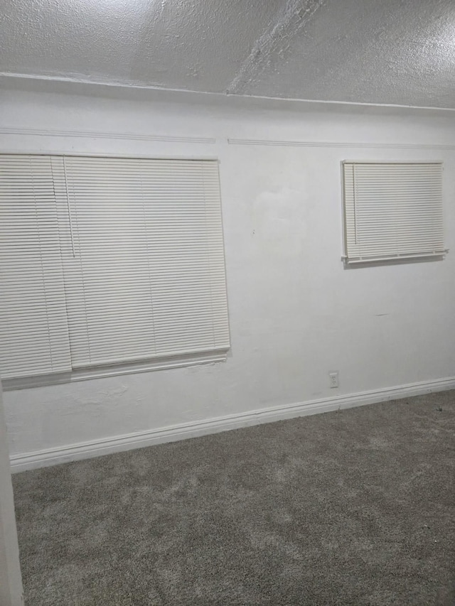 carpeted empty room featuring baseboards and a textured ceiling