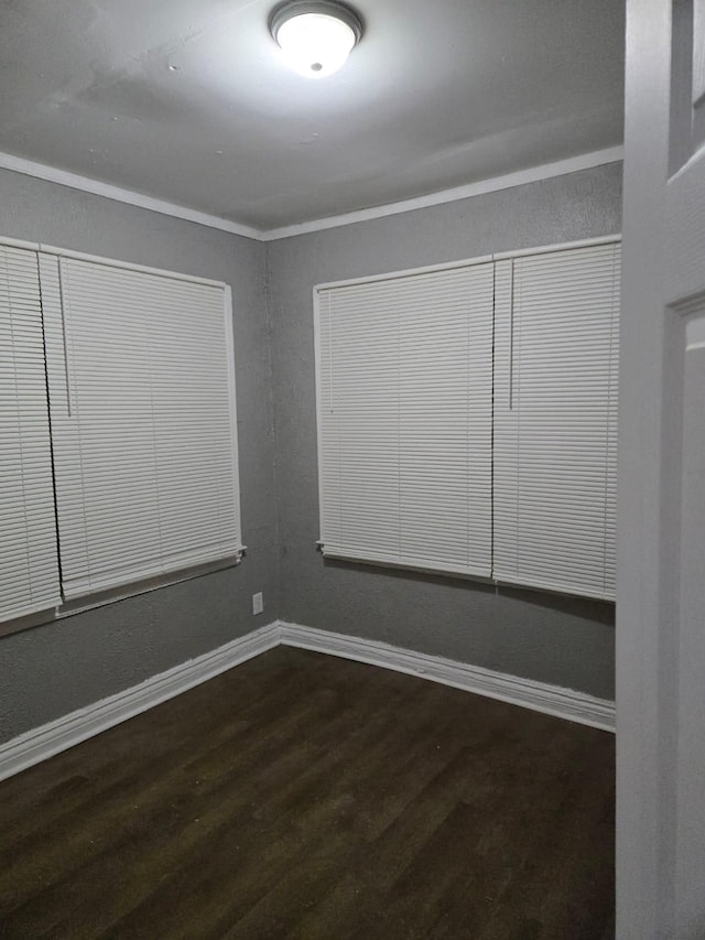 unfurnished room featuring crown molding, dark wood-style floors, and baseboards