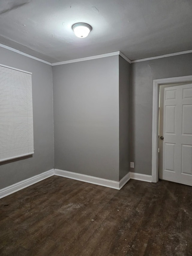 empty room with crown molding, wood finished floors, and baseboards