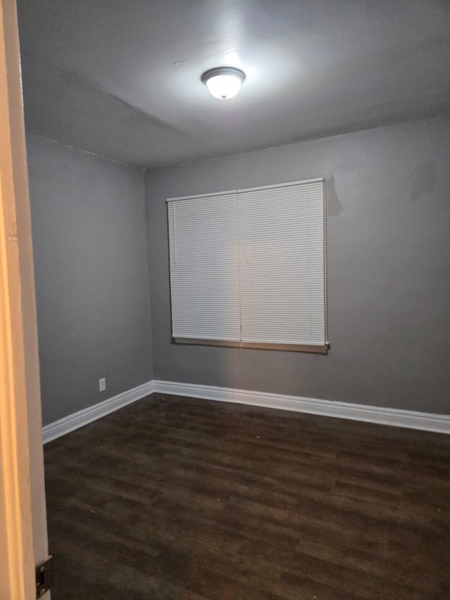 unfurnished room featuring dark wood-style floors and baseboards