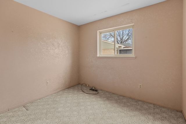 spare room featuring carpet and a textured wall