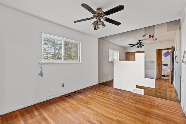 unfurnished room featuring visible vents, light wood-type flooring, and ceiling fan