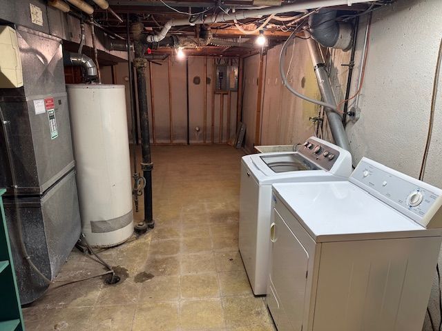 clothes washing area featuring gas water heater, heating unit, washing machine and dryer, and laundry area