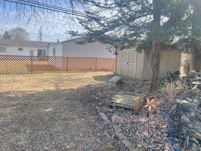 view of yard with an outdoor structure, fence, and a shed