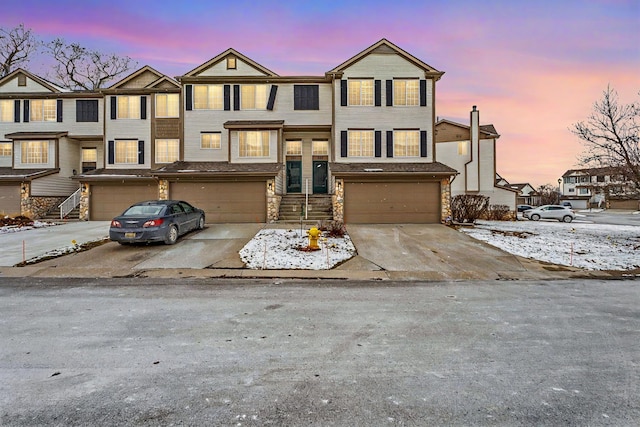 multi unit property with concrete driveway, an attached garage, and stone siding