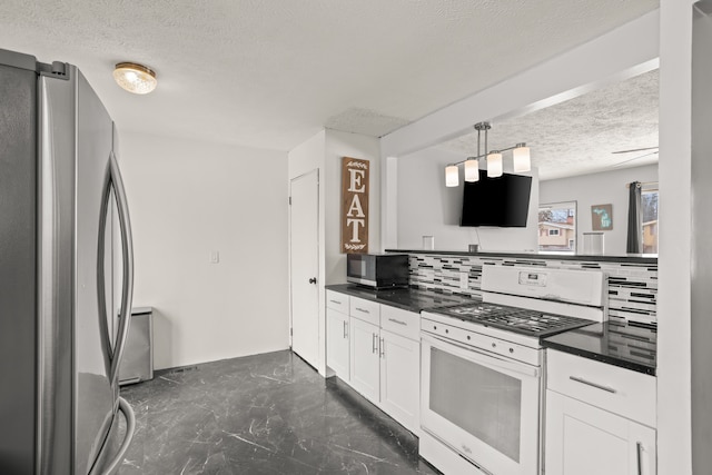 kitchen with tasteful backsplash, dark countertops, white gas range, and freestanding refrigerator