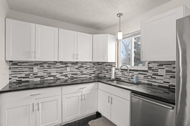 kitchen with a sink, stainless steel appliances, dark countertops, and white cabinets