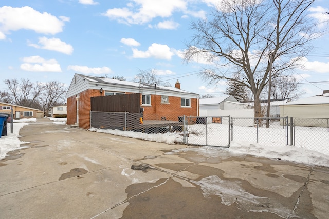 exterior space featuring brick siding, a chimney, a fenced front yard, and a gate