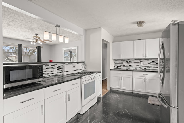 kitchen featuring tasteful backsplash, dark countertops, appliances with stainless steel finishes, and white cabinets