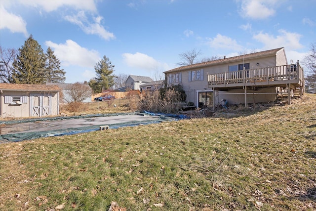 view of yard featuring a storage unit, a covered pool, fence, an outdoor structure, and a wooden deck