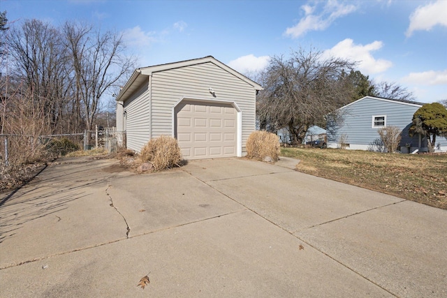 view of property exterior featuring concrete driveway, fence, a garage, and an outbuilding