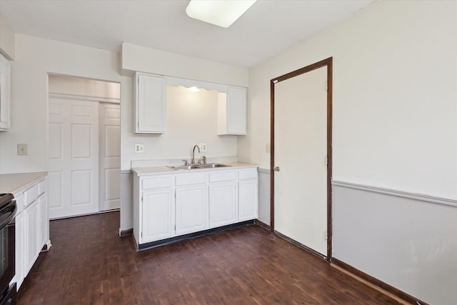 kitchen with light countertops, black electric range, dark wood-style floors, white cabinets, and a sink