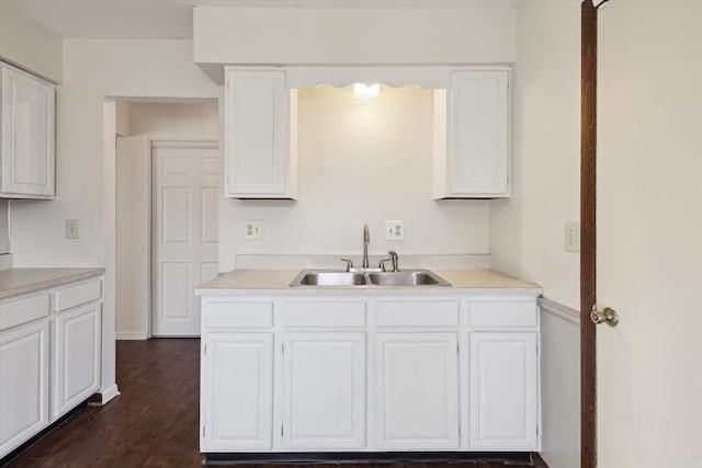 kitchen with dark wood finished floors, white cabinets, light countertops, and a sink