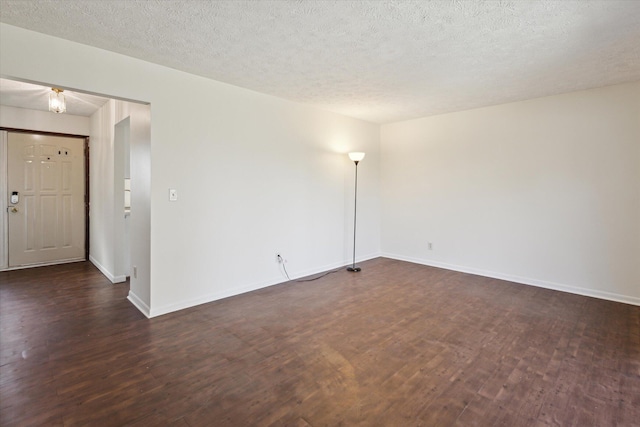 spare room with dark wood-style floors, a textured ceiling, and baseboards