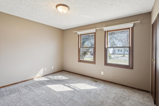 carpeted spare room with a textured ceiling and baseboards