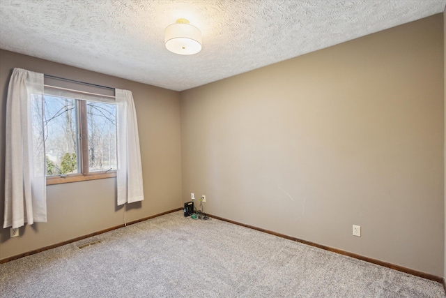 spare room with carpet flooring, visible vents, baseboards, and a textured ceiling