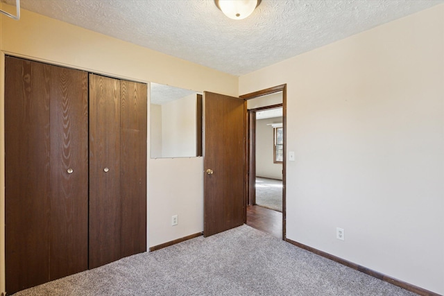 unfurnished bedroom featuring a closet, carpet floors, a textured ceiling, and baseboards