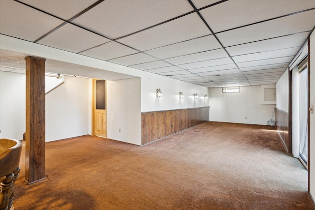 basement featuring wainscoting, a paneled ceiling, wood walls, and carpet floors