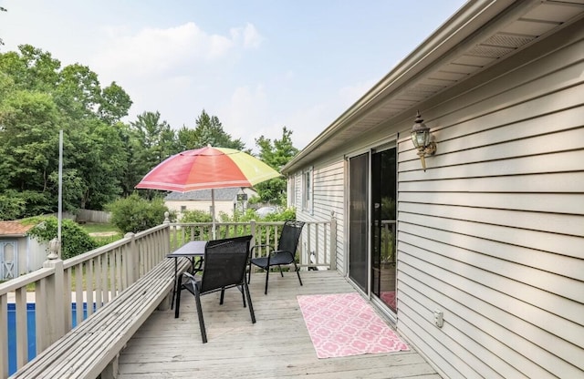 deck with outdoor dining area and an outdoor pool