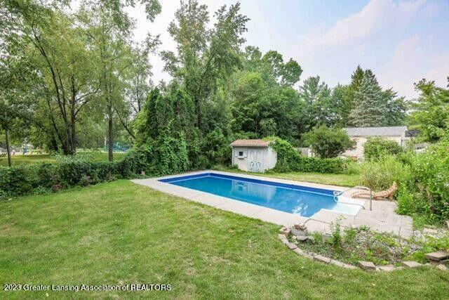 outdoor pool featuring an outbuilding, a storage shed, and a yard