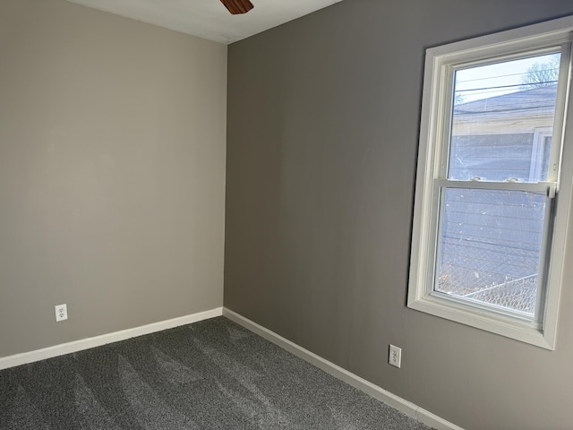 spare room featuring baseboards, dark carpet, and ceiling fan