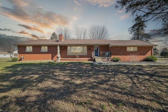 ranch-style house featuring brick siding, a chimney, and a front lawn