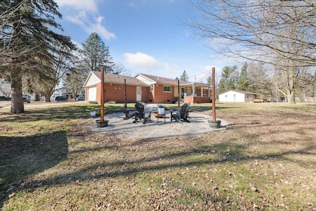 rear view of property featuring a yard, a patio, brick siding, and an outdoor fire pit