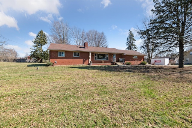 view of front facade with brick siding, a chimney, and a front lawn