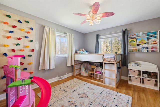 bedroom featuring a ceiling fan, visible vents, wood finished floors, and baseboards