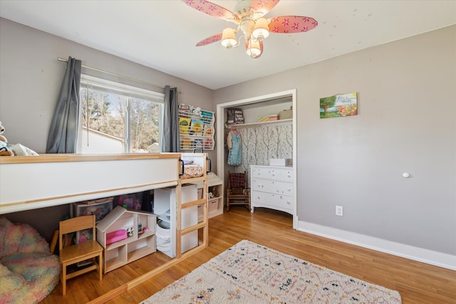 bedroom featuring ceiling fan, a closet, baseboards, and wood finished floors