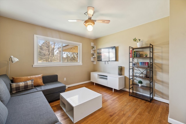 living area with a ceiling fan, wood finished floors, and baseboards