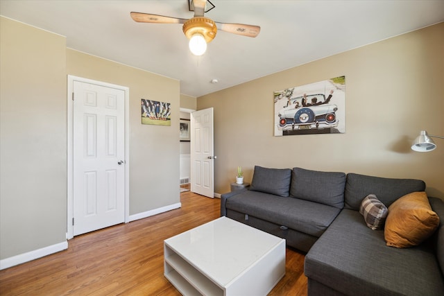 living room with ceiling fan, baseboards, and wood finished floors