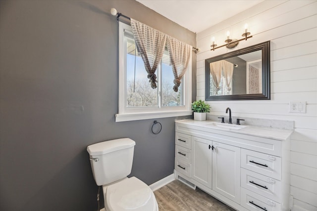 bathroom featuring vanity, toilet, wood finished floors, and baseboards